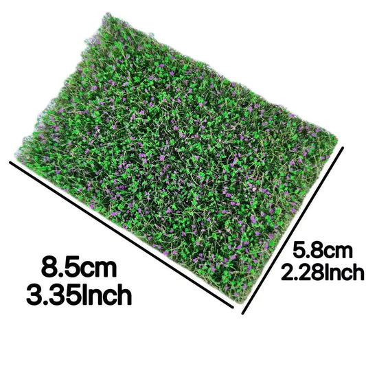 Rectangular artificial miniature grass mat with tiny purple flowers, marked with 8.5cm × 5.8cm size measurements for diorama micro landscape craft project reference