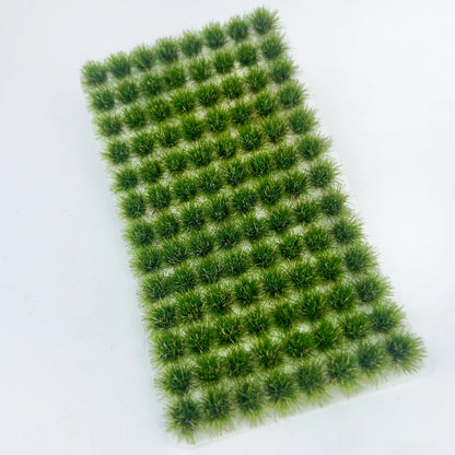 Pack of 104 self-adhesive static grass tufts sheet, 10.8cmx6cm overall size with deep vibrant green mini foliage clumps, close-up detail display, static grass tufts, miniature diorama supplies, wargame terrain material, model railway grass, self-adhesive grass clusters, scale model scenery, warhammer terrain, hobby craft grass