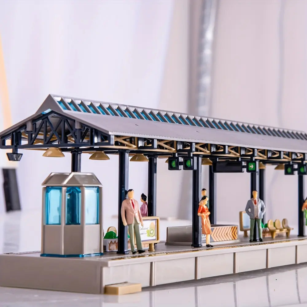 Full panoramic shot of scale model train station platform diorama layout, decorated with multiple waiting miniature people figures, complete railway station scenery for hobby diorama craft and wargame terrain