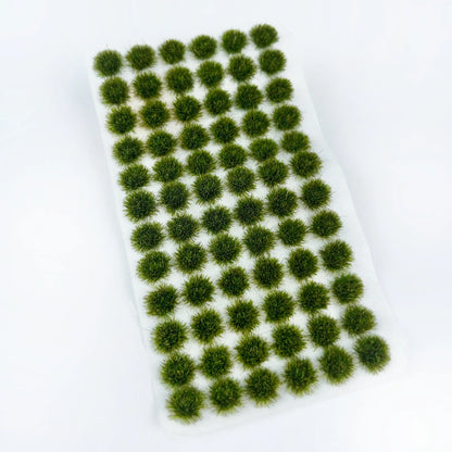 Unpacked sheet of dark forest green self-adhesive static grass tufts on clean white background, dense fine fiber bush clumps for military diorama, wargame terrain and scale railway scene landscaping