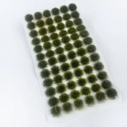 Single sheet of dark forest green self-adhesive static grass tufts on white backing, loose product shot without blister packaging, realistic bush clump material for military diorama, wargame and model railway terrain making