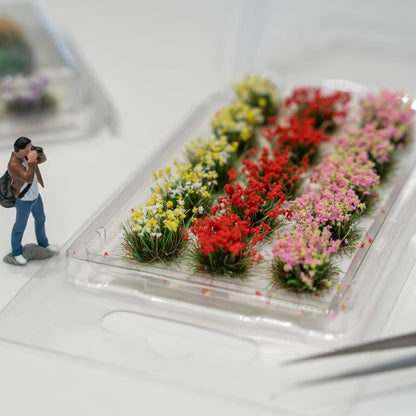 Pink mixed tiny flower tuft held by tweezers, pre-glued backing easy to apply on dollhouse and model scenes
