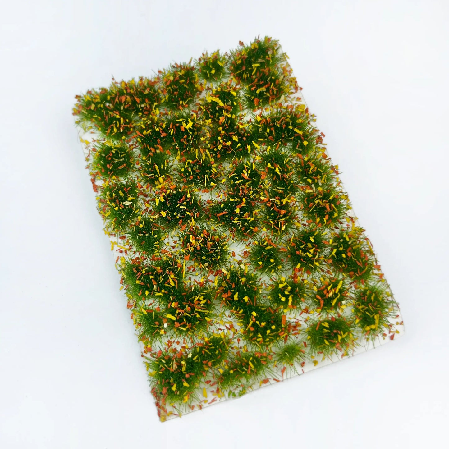 Bright fairy tale castle stream meadow diorama scenery built with colorful static grass tufts and static grass mat, vibrant miniature landscape terrain for scale model building, wargame tabletop base, railway layout scenery and diorama craft hobby creation

