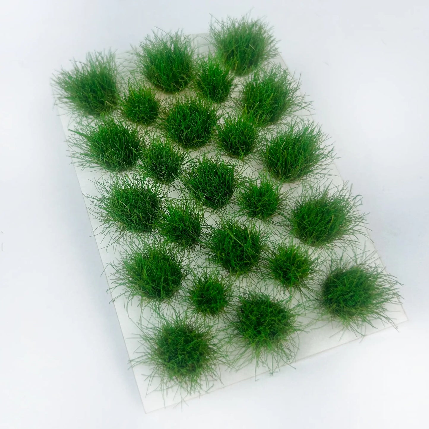 Self-adhesive grass tuft sheet with size dimension labels 8.5cm x 5.8cm, spring green miniature wild grass clusters, scale reference product shot for diorama hobby terrain material