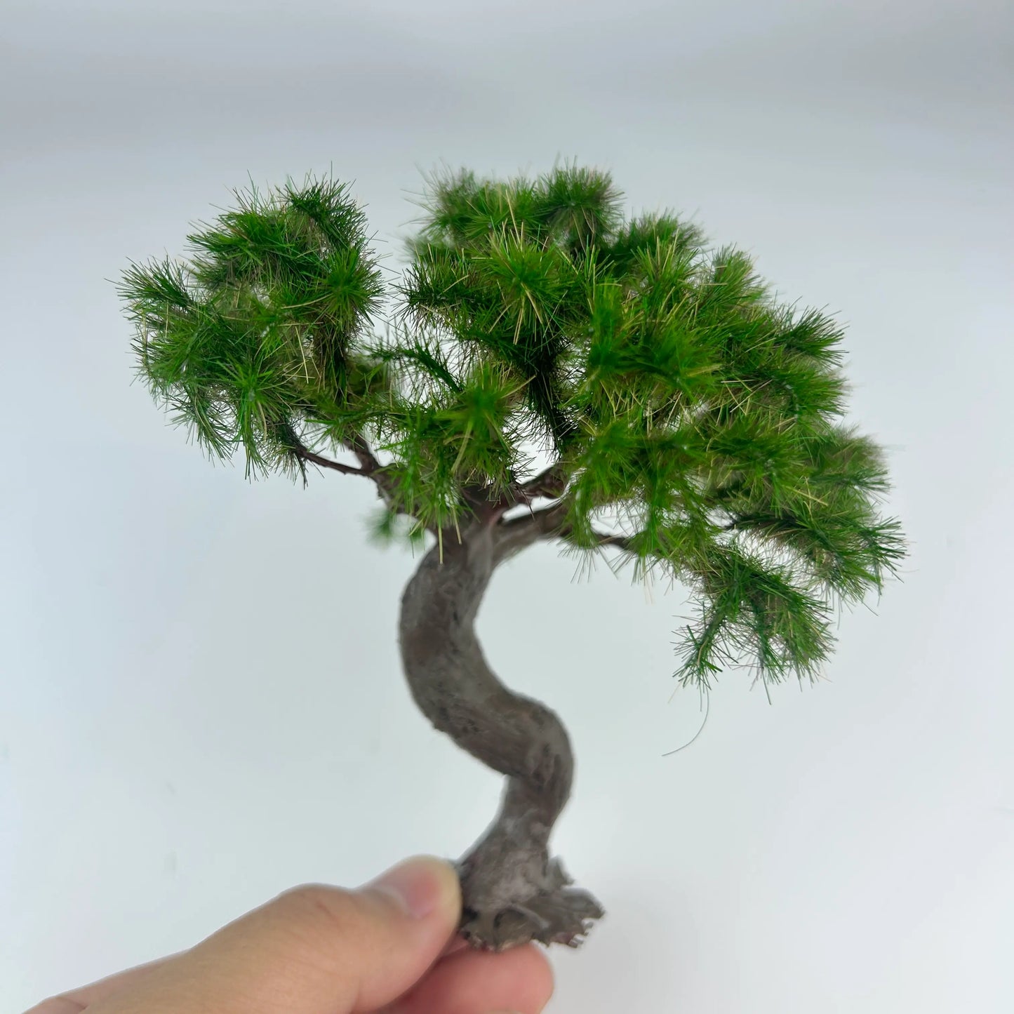 Twisted miniature pine bonsai set inside square base micro landscape with static grass and rock details for display and scene making
