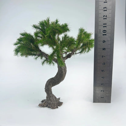 Close-up hand holding curved textured bark trunk of mini bonsai pine model, realistic rough wood grain for oriental scene detail making