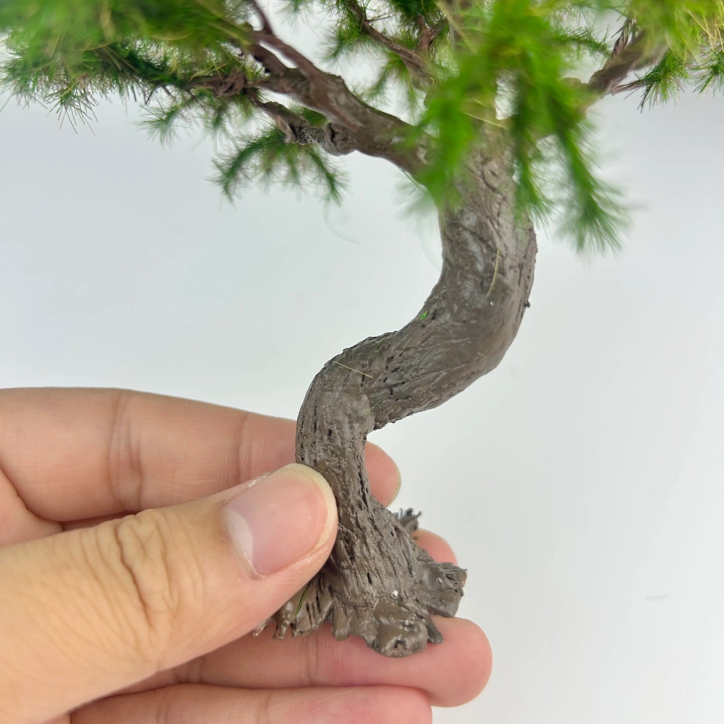 Miniature twisted bonsai pine arranged with wooden fence and country path to build misty oriental rural diorama landscape