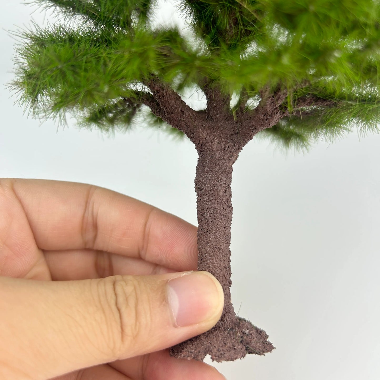 Macro close-up of branches and green needle foliage on miniature pine tree model, natural layered structure for wargame terrain
