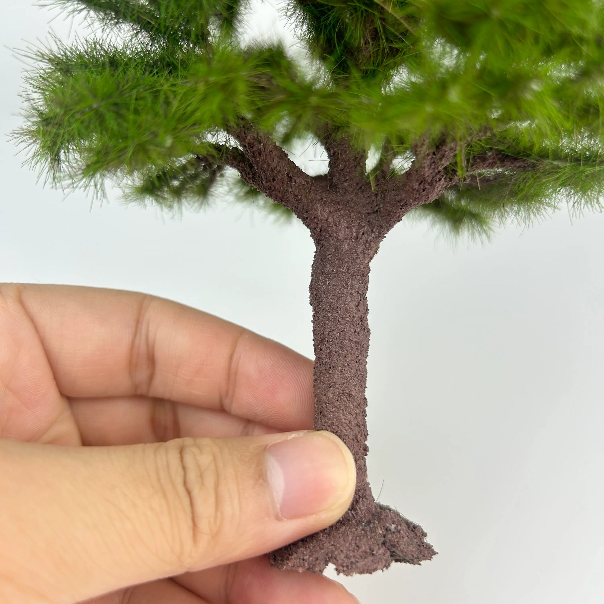 Macro close-up of branches and green needle foliage on miniature pine tree model, natural layered structure for wargame terrain
