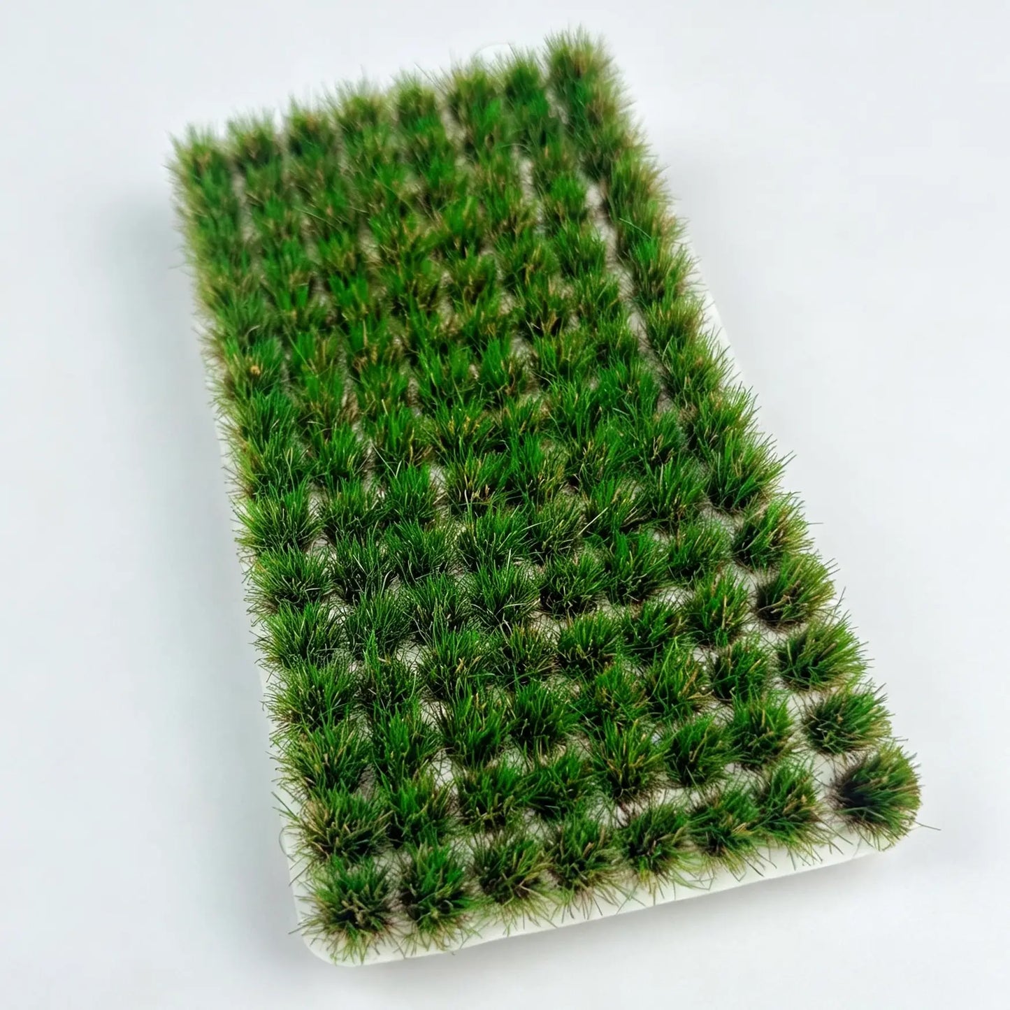 Deep green static grass tufts, lifelike miniature ground cover material for tabletop wargaming and military diorama
