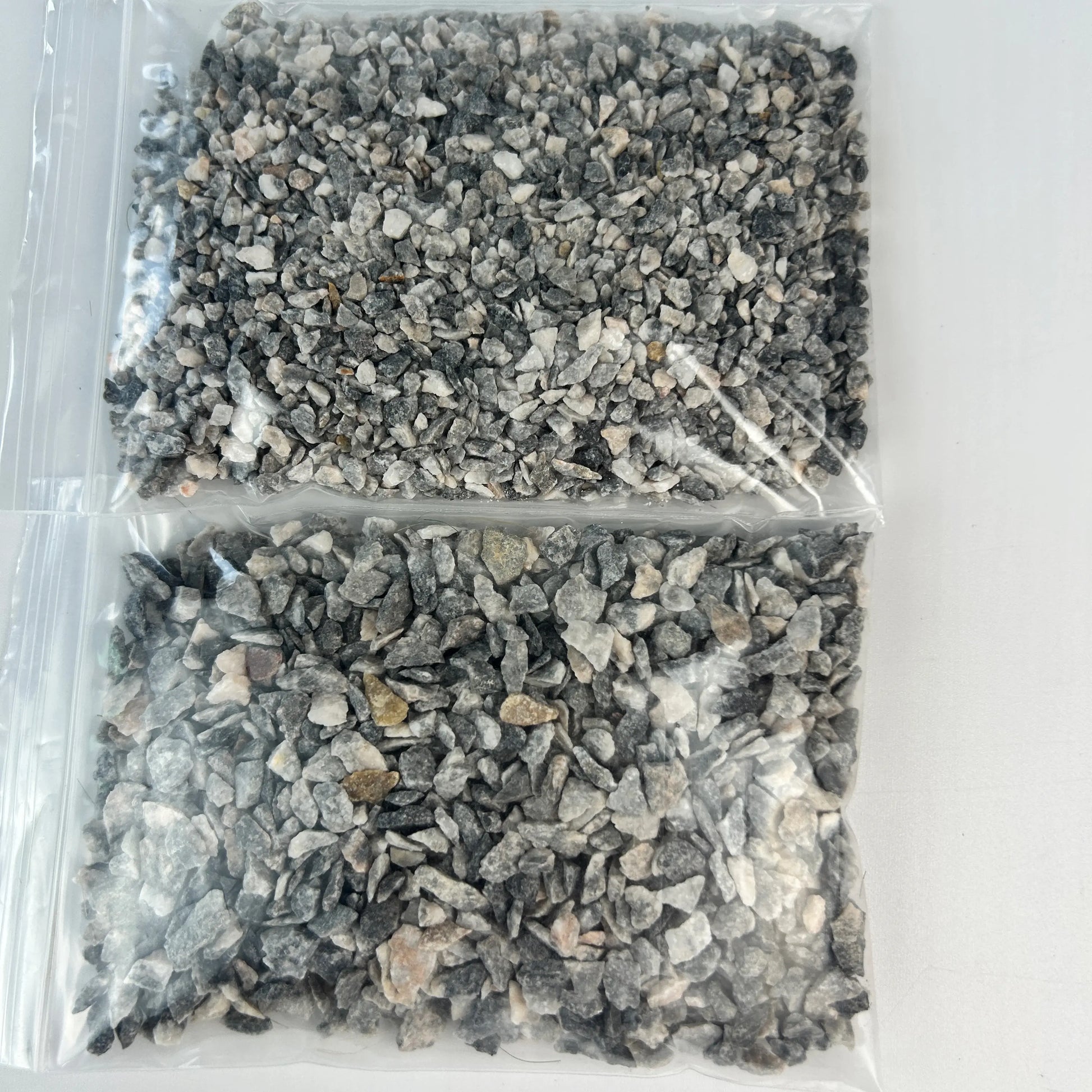 Close‑up shot of grey mixed‑color miniature railway ballast gravel texture 