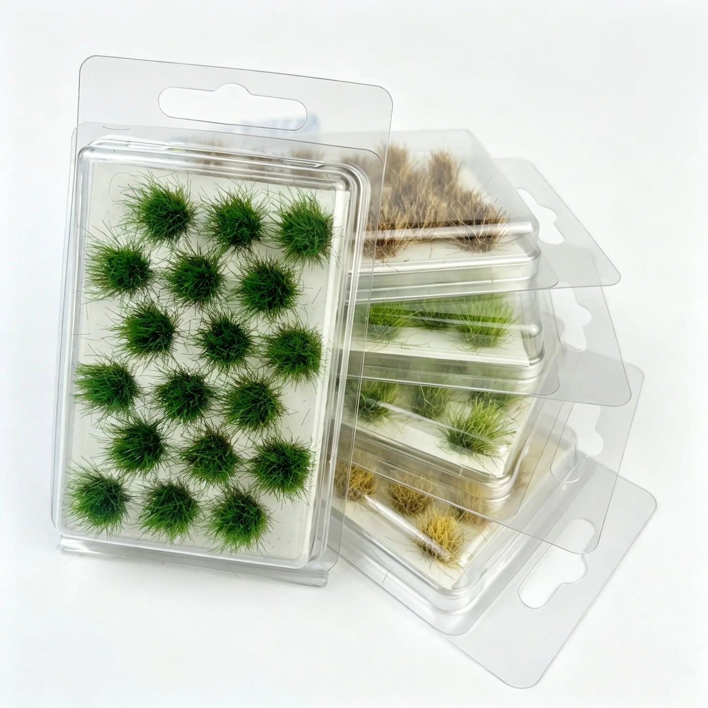 Mixed tone round static grass tuft sheets stacked in clear hanging plastic storage boxes, self-adhesive mini foliage clumps for wargame base, diorama landscape and scale model railroad scenery crafting, bright green, olive and dry brown miniature grass clusters