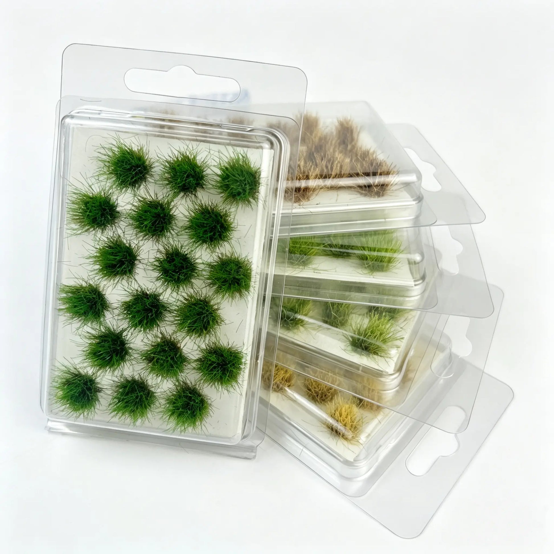 Mixed tone round static grass tuft sheets stacked in clear hanging plastic storage boxes, self-adhesive mini foliage clumps for wargame base, diorama landscape and scale model railroad scenery crafting, bright green, olive and dry brown miniature grass clusters
