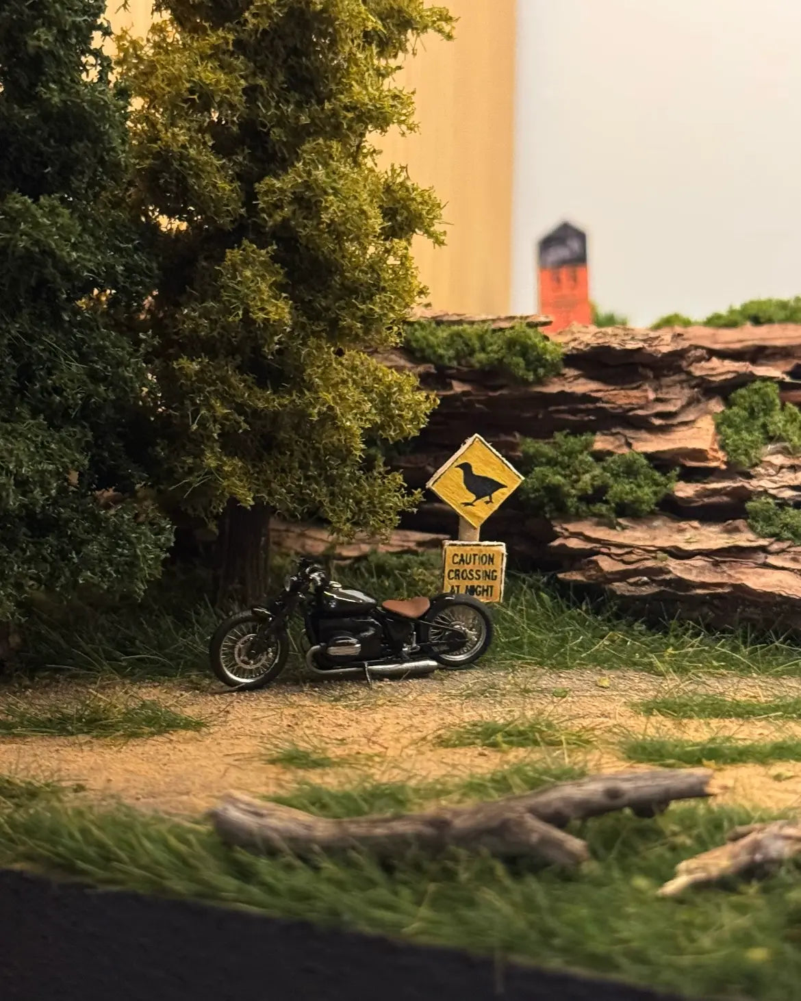 Static grass tufts creating a realistic roadside scene beside a miniature motorcycle and woodland landscape.