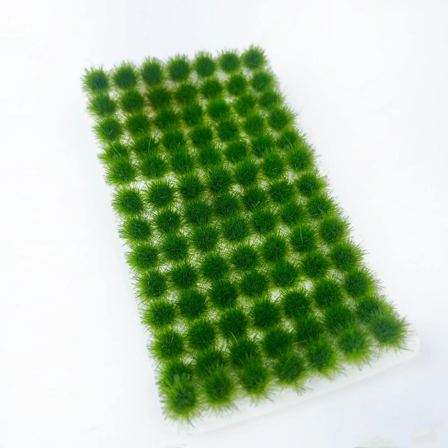 Self-adhesive summer vibrant deep green static tuft grass sheet with dense plump grass tufts, high-detail miniature terrain material for farm, forest and realistic tabletop wargame landscape

