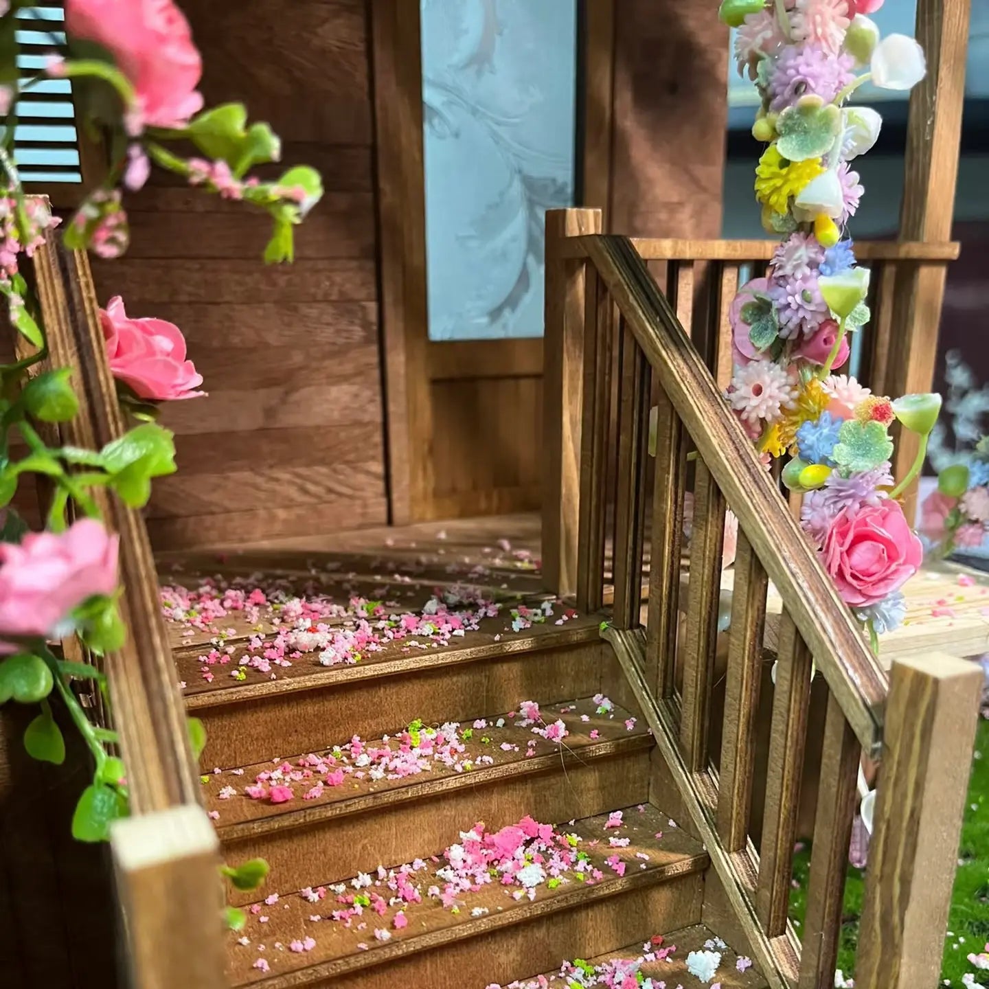 Wooden dollhouse staircase decorated with mini flower tufts and scattered petals for delicate interior scene effect