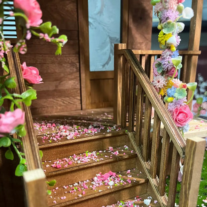Wooden dollhouse staircase decorated with mini flower tufts and scattered petals for delicate interior scene effect