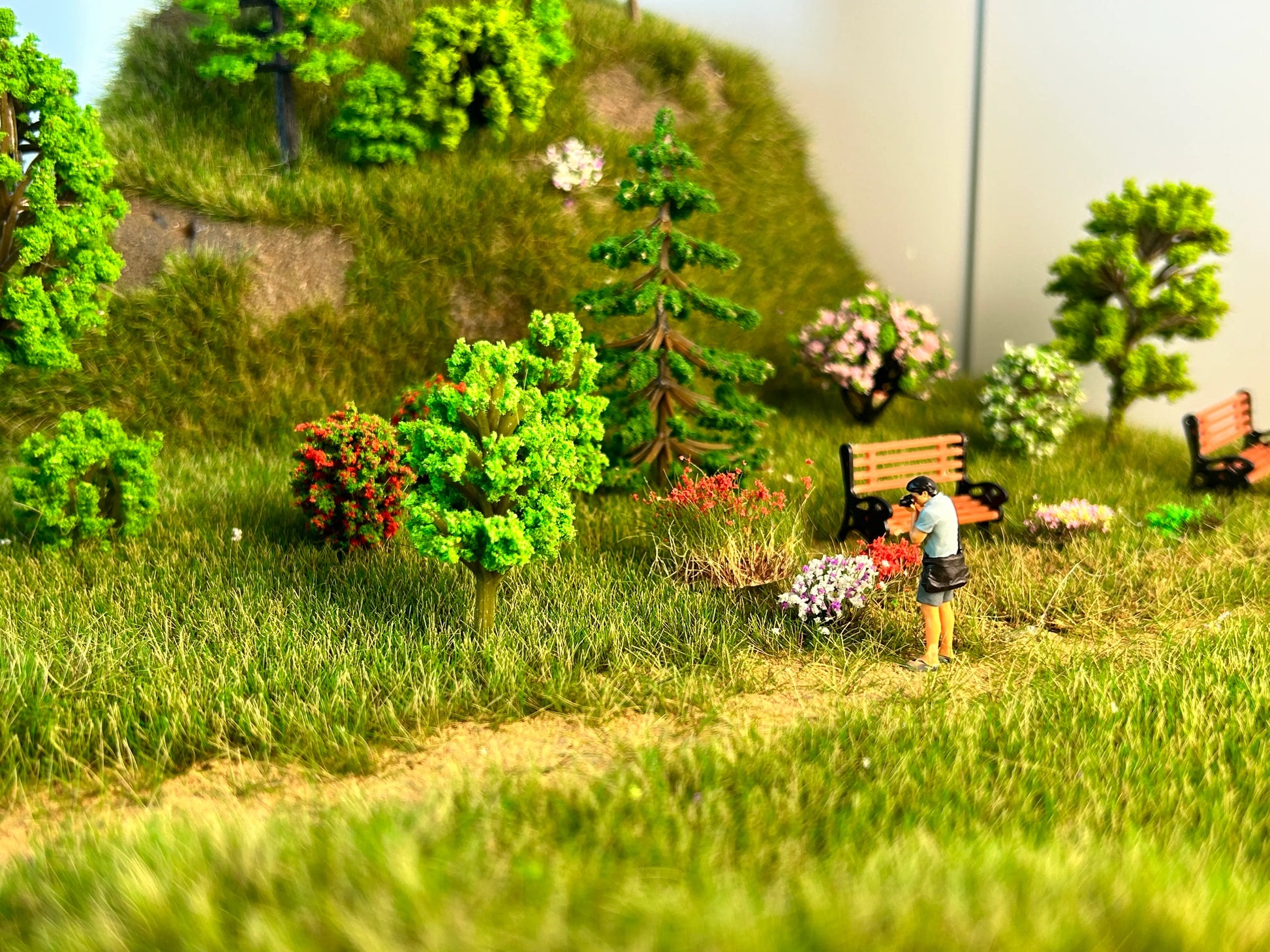 Finished garden scenery built with static grass mat, realistic lawn terrain sheet matched with miniature trees, flower tufts and figure for scale model diorama, wargame hobby creation